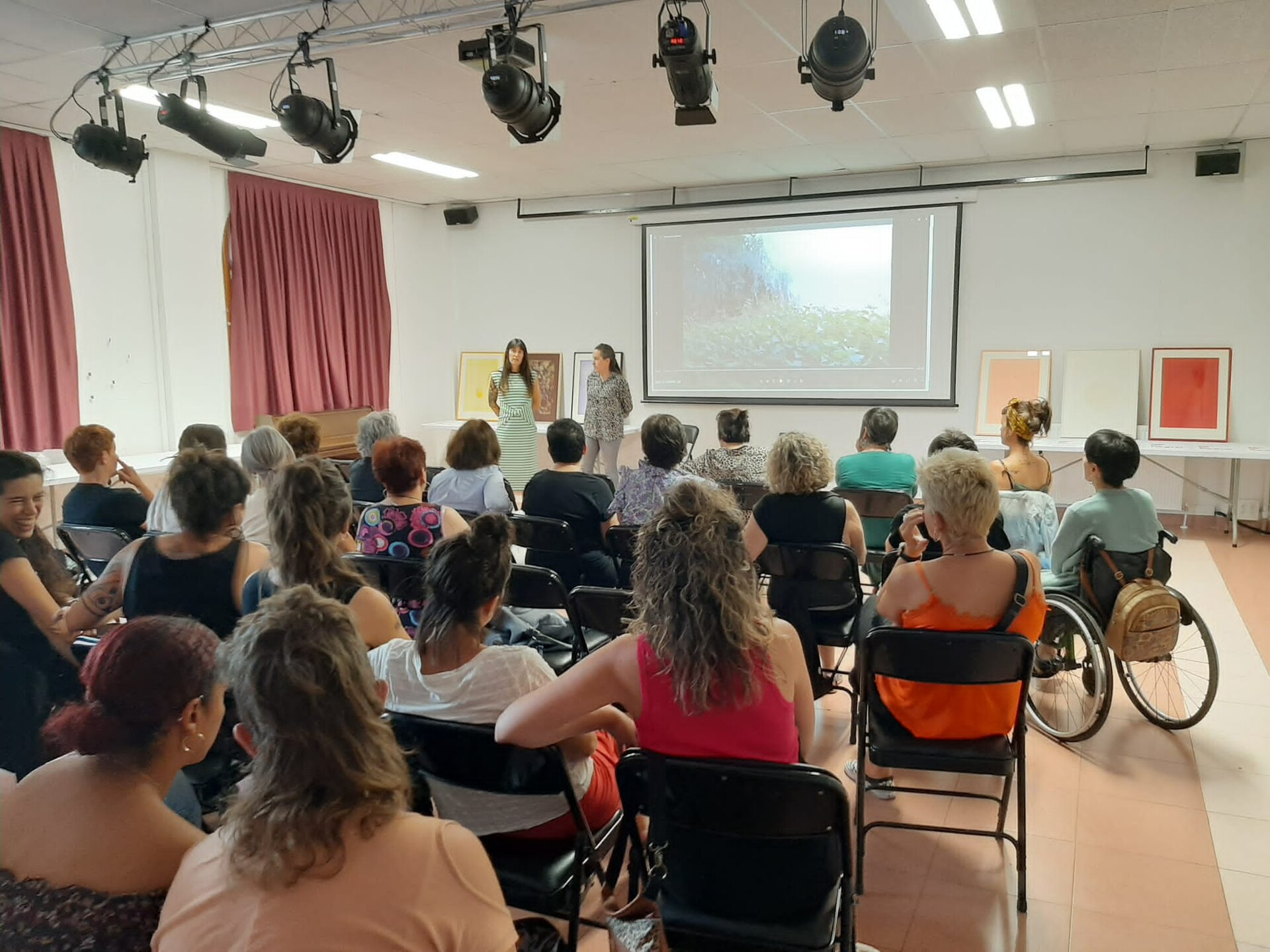 Deux intervenantes présentent un film devant un public assis